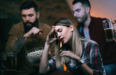 Sport fans feeling disappointed after their team has lost a match. Group of disappointed sport fans feeling sad after their team has lost a game. Focus is on woman.